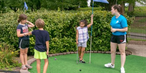 A group of youth play mini-golf