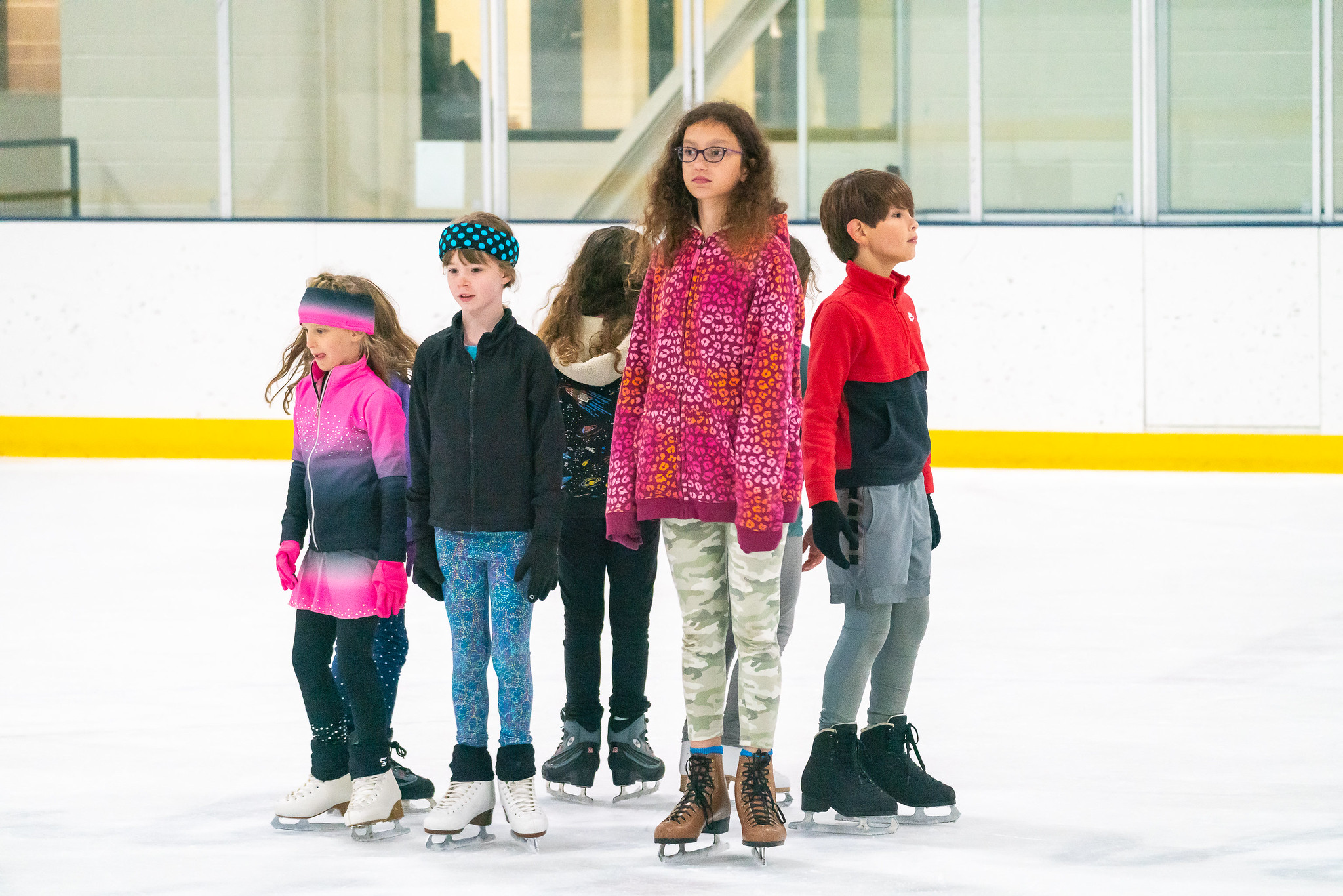 kids learning to skate standing in a circle on the ice 