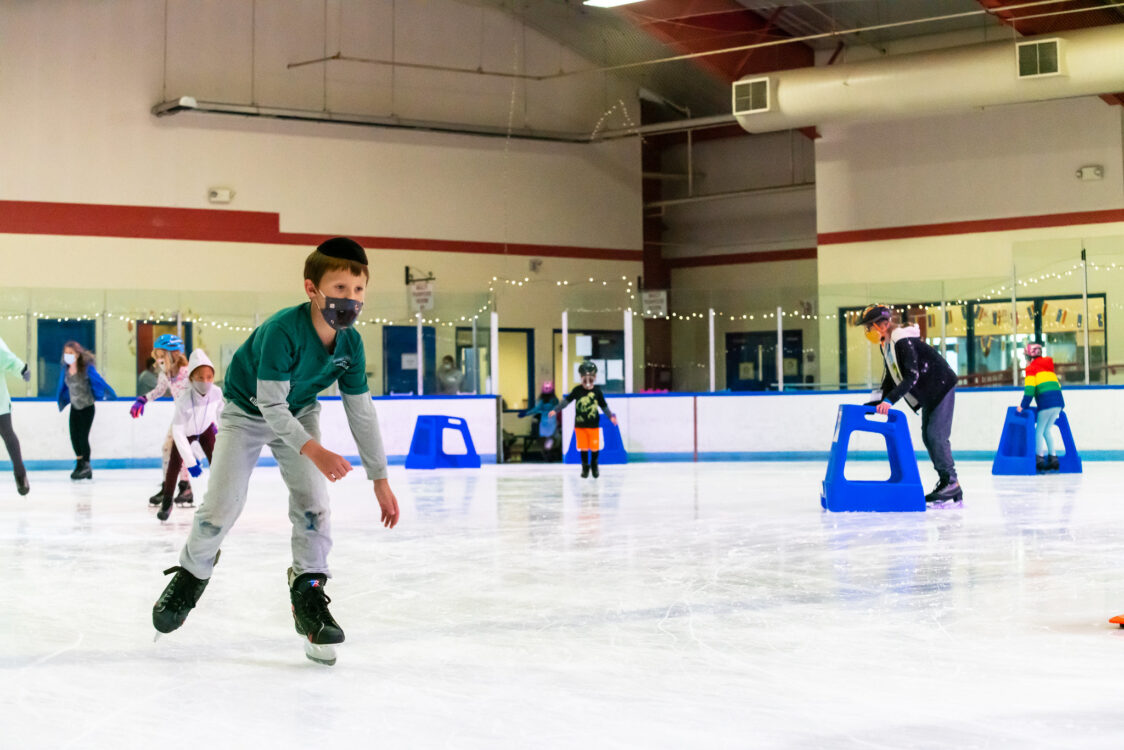 young adult zooming around the ice rink at camp