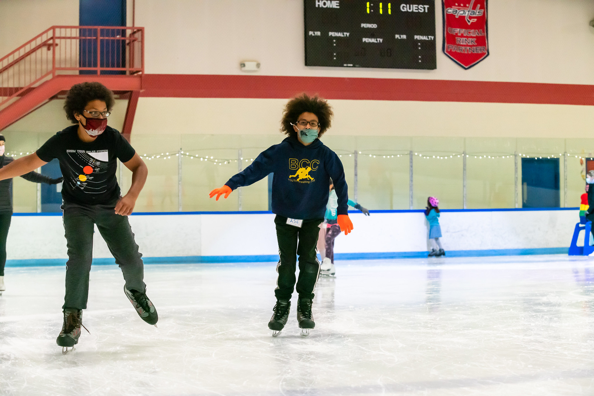 two kids skating around ice rink at wheaton ice camp