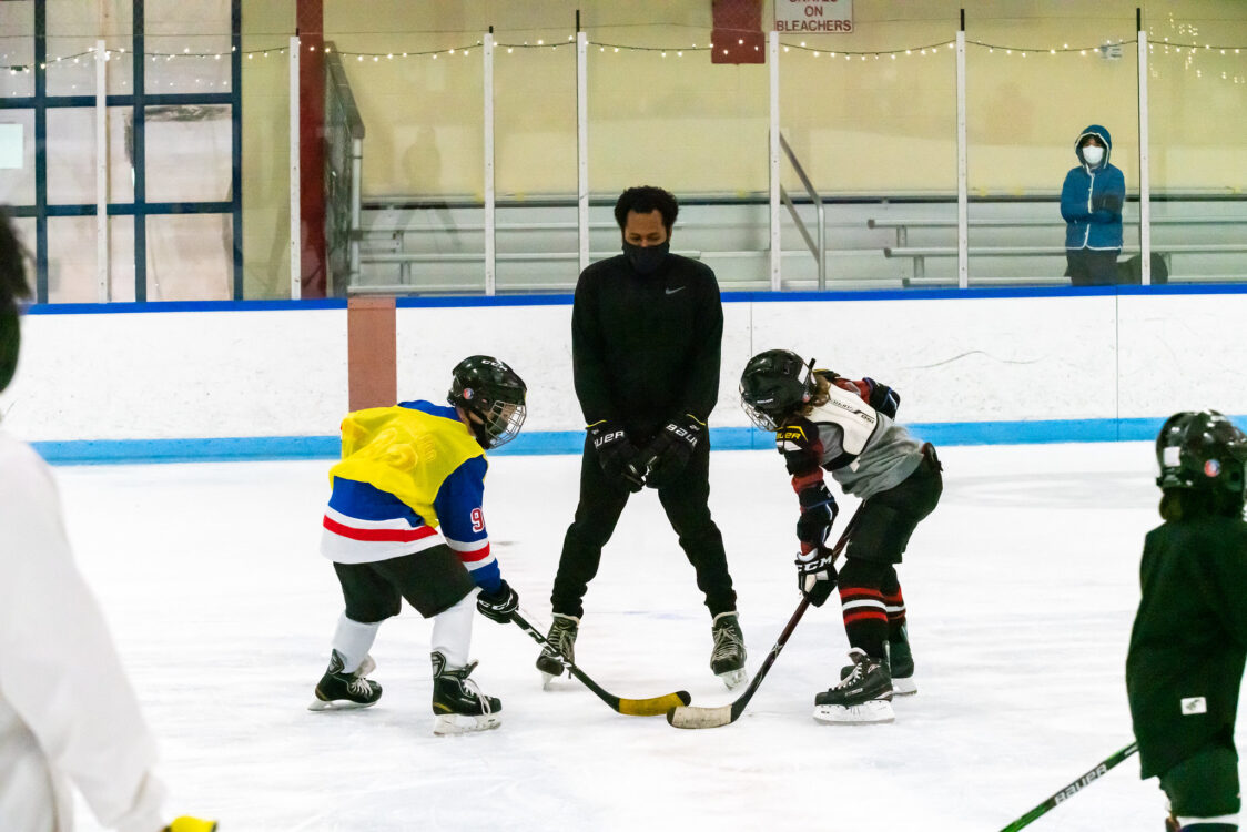 referee and two kids at faceoff hockey camp