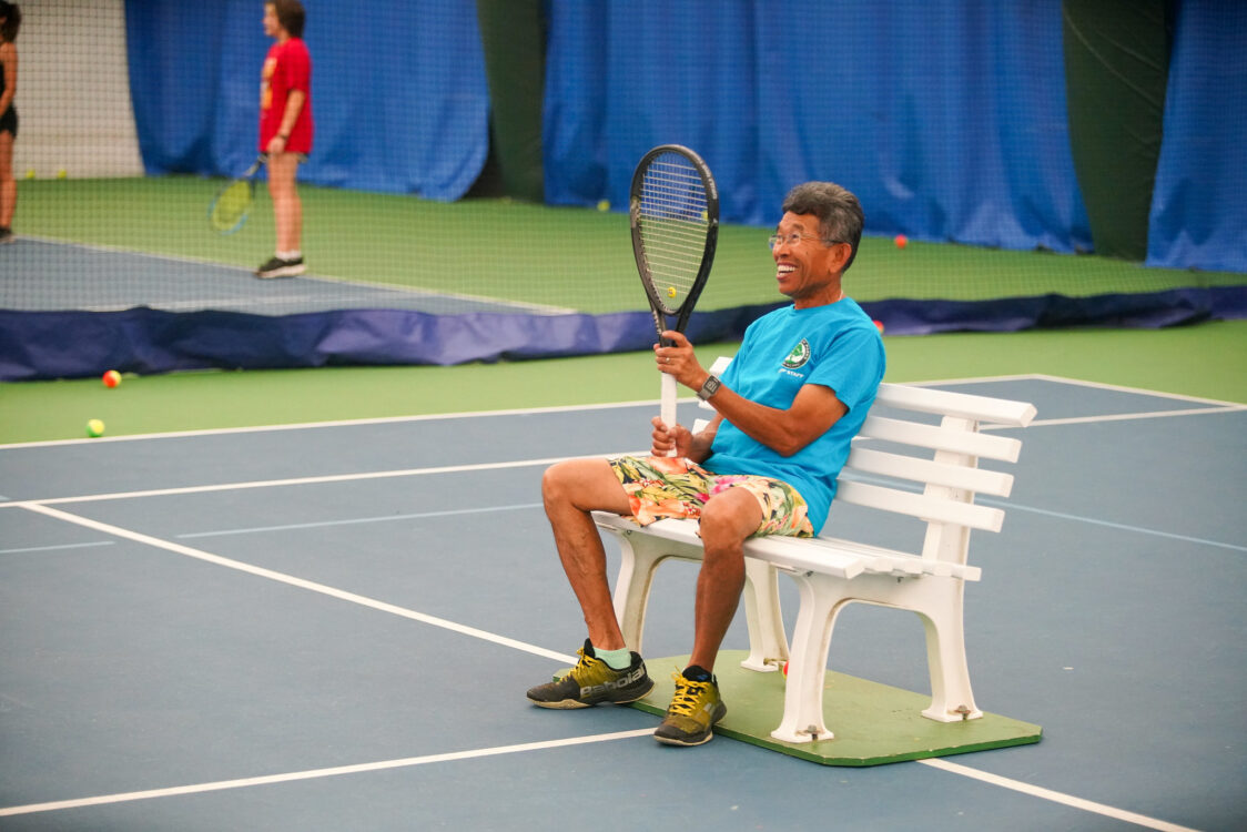 tennis instructor holding up a racquet at summer camp