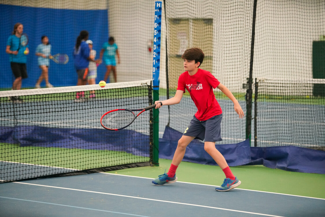 teen practicing returning a tennis ball at summer camp