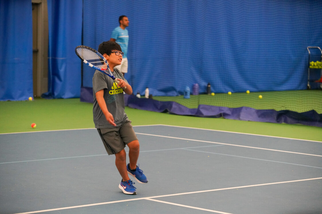 camper returning tennis serve at summer camp