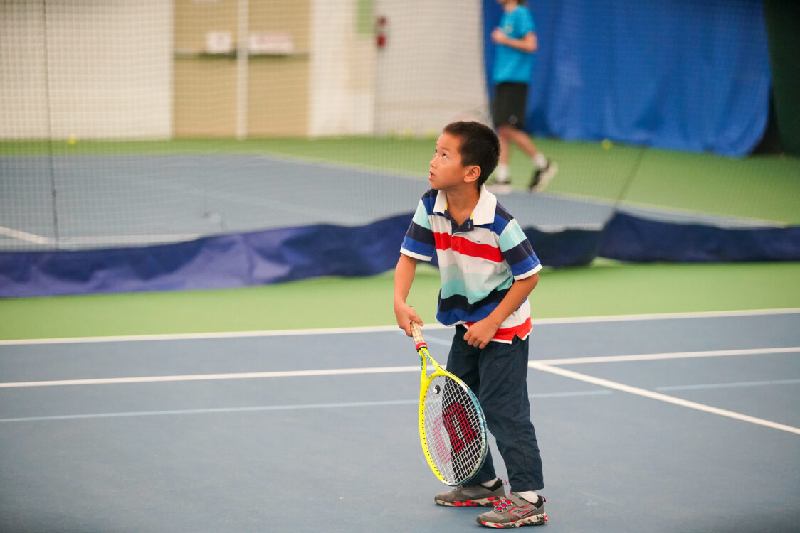 camper serving at tennis at indoor tennis summer camp