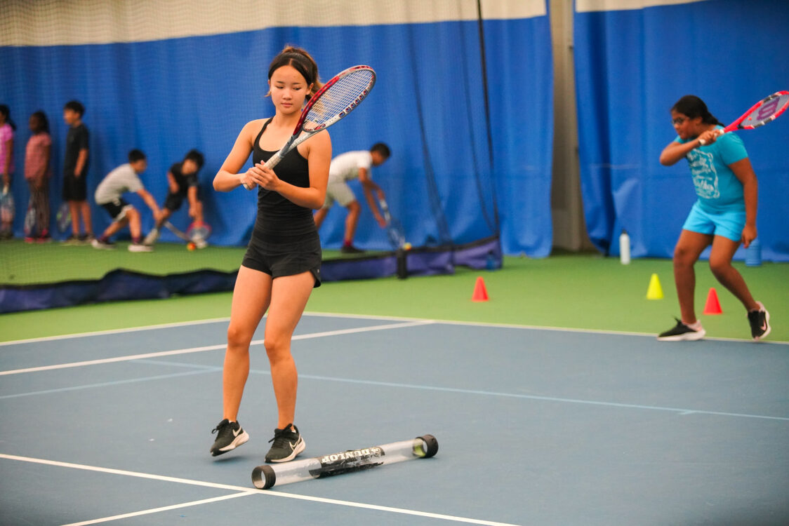 teen moving around the court practcing tennis