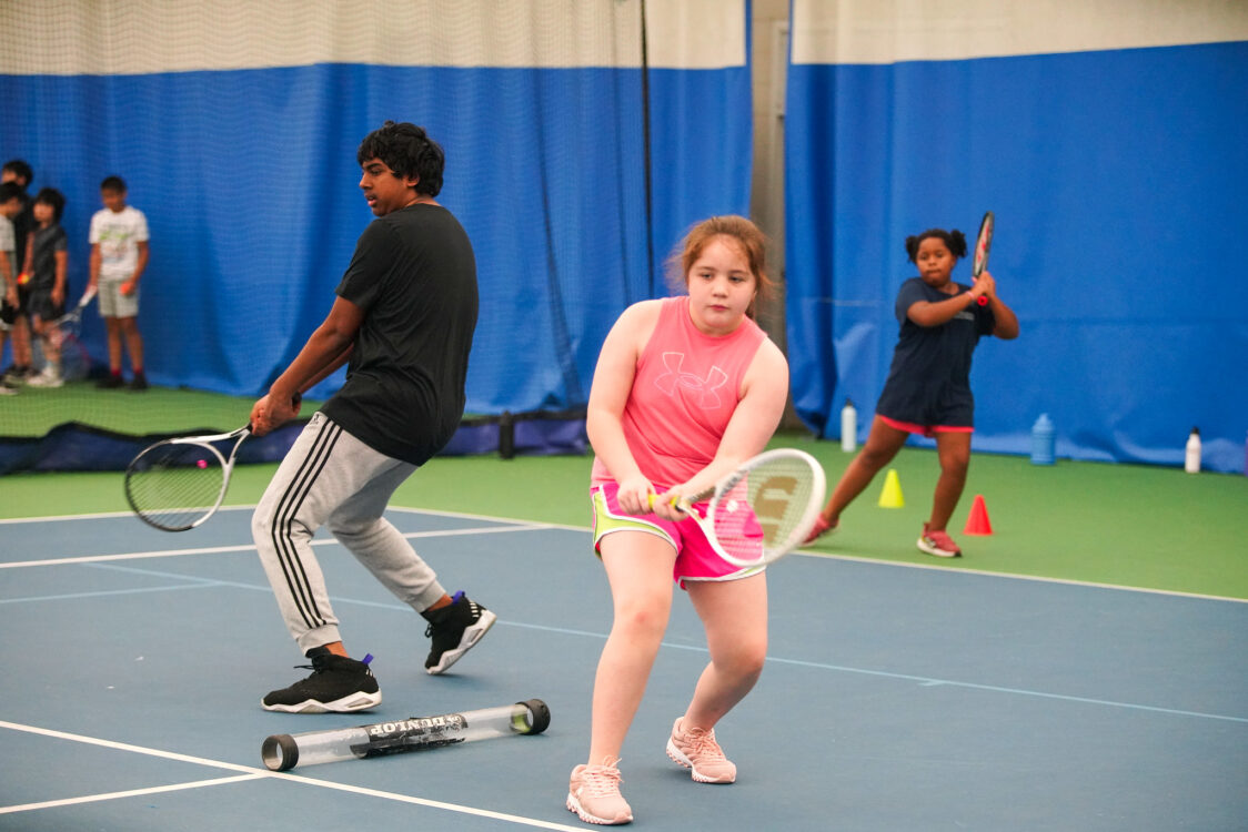 child retuning a tennis ball at tennis camp