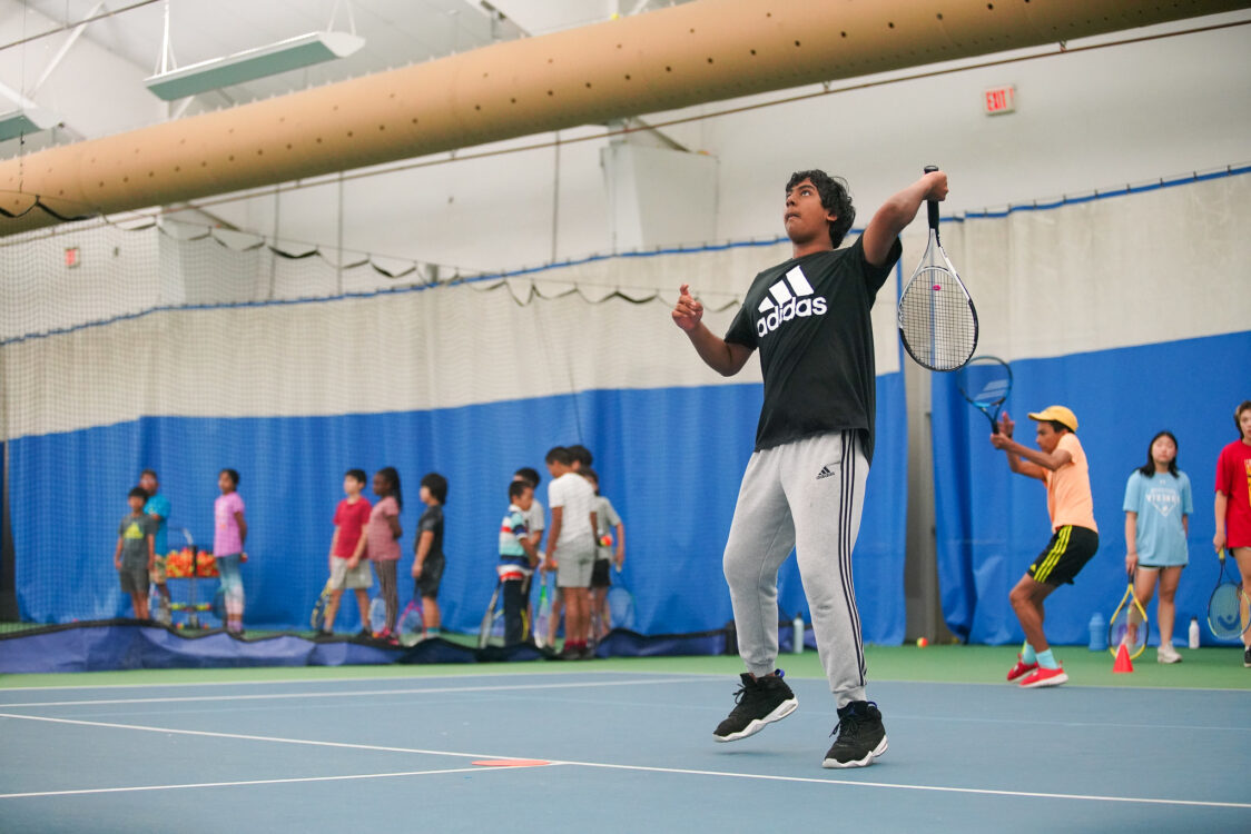 teen jumping up to hit tennis camp at tennis camp