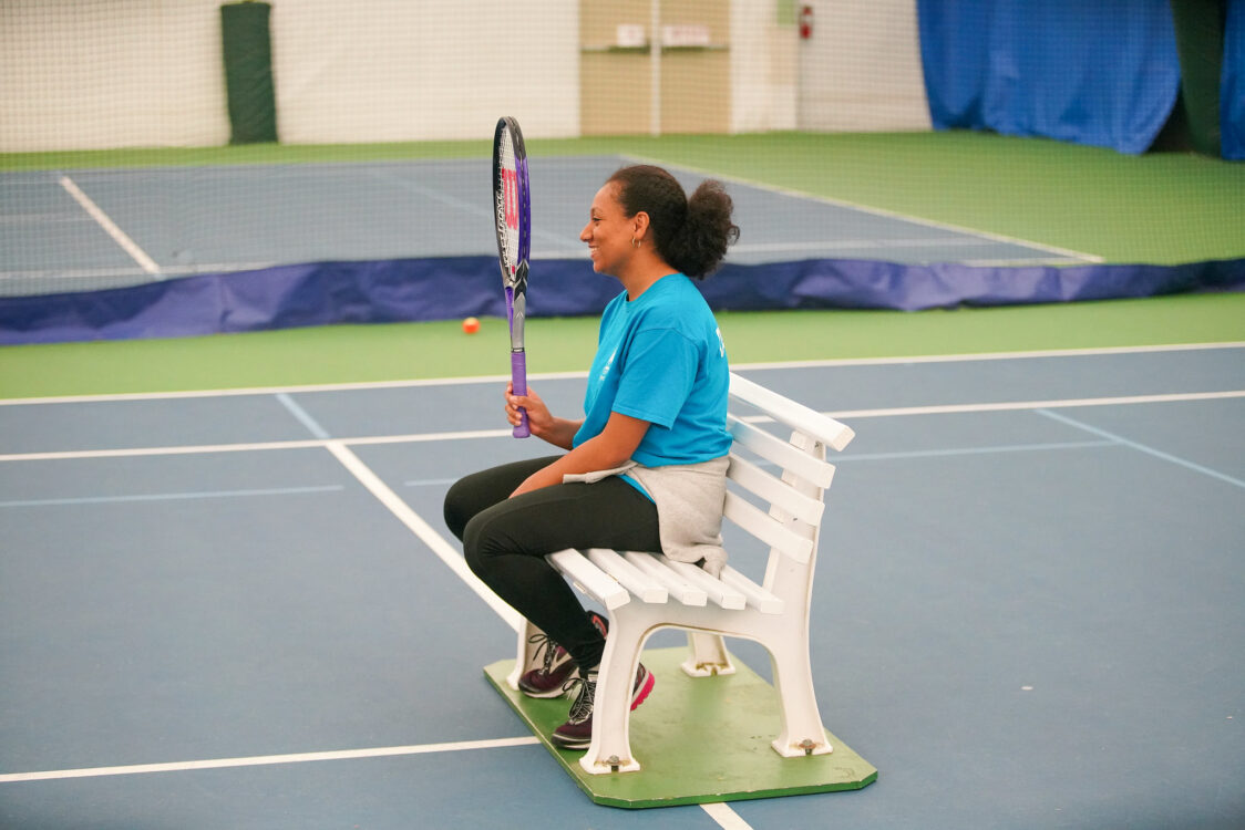 instructor holding up a tennis racquet at indoor tennis camp