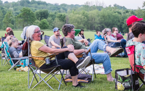 audience members sitting in their chairs turned towards the stage laughing