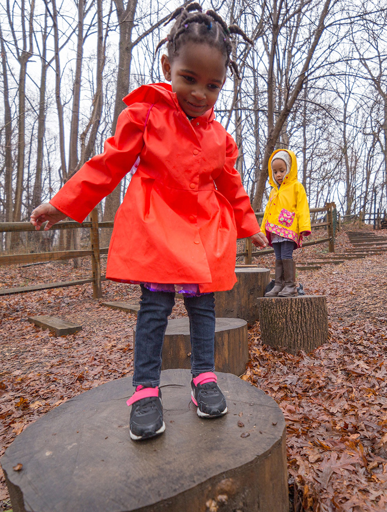 child playing on wood stump