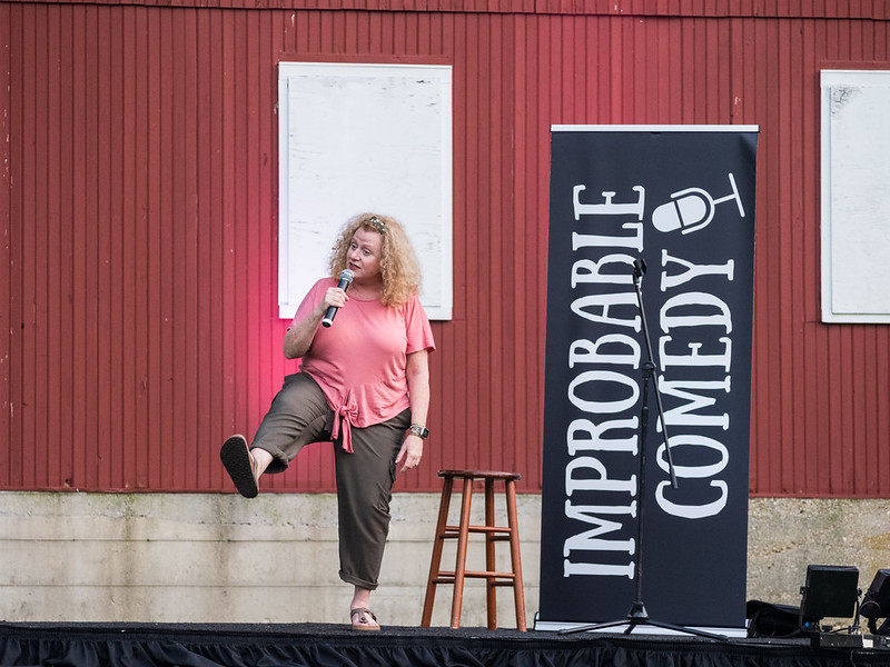 comedian on stage with foot kicked out acting out a scene