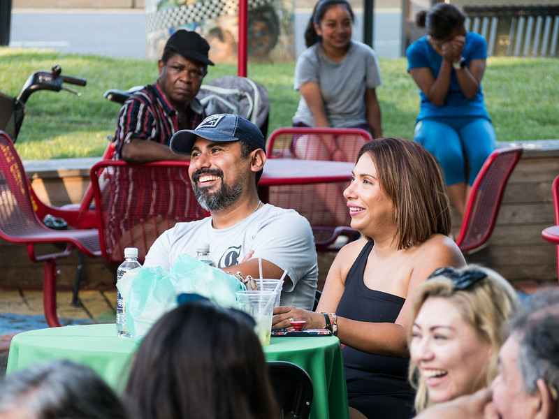 couple seated at table looking toward stage and laughing