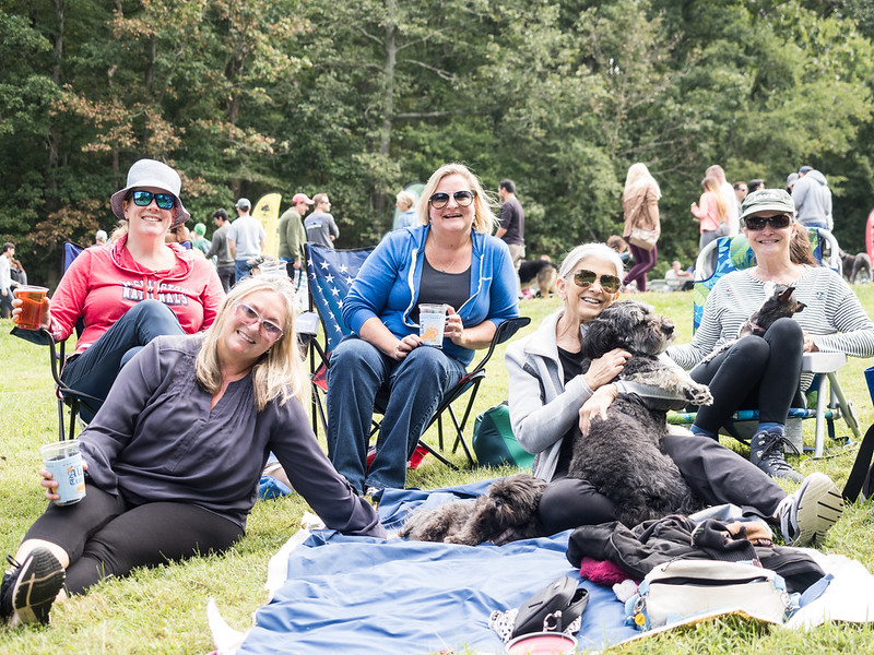 family and friends sitting in the grass with their dog at the ale trail event