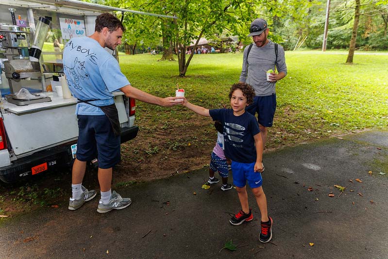 child receiving a shaved ice cone at Happenstance Theater production in summer of 2023