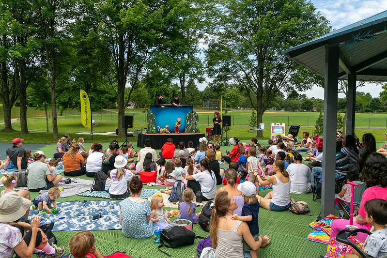 group of park visitors watching a puppet show.